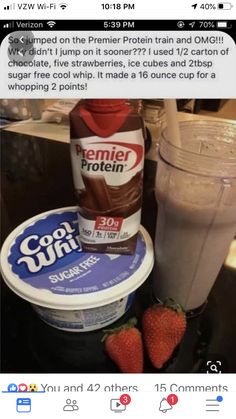 a cup of ice cream next to some strawberries and a bottle of protein drink