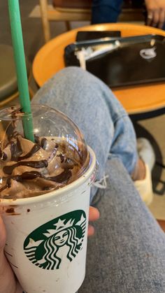 a person holding a starbucks drink in their hand with chocolate swirls on the top