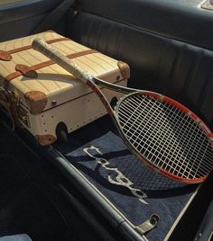 an old suitcase and tennis racket are in the back seat of a vintage car