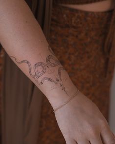 a woman's arm with a snake tattoo on her left wrist and the word love written in cursive writing