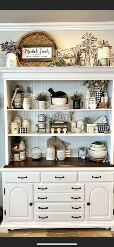 a white hutch filled with lots of dishes and other things on top of it