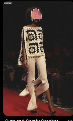 a woman is walking down the runway wearing a crochet sweater and matching shoes