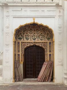 an ornate doorway with two doors and rugs on the ground in front of it