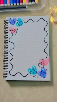 a notebook with hearts drawn on it next to some crayon markers and colored pencils