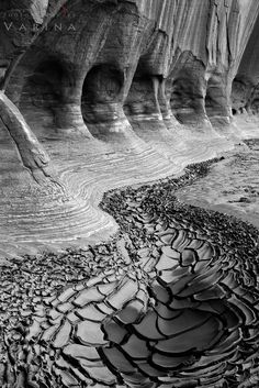 a black and white photo of water running through the rocks in front of some cliffs