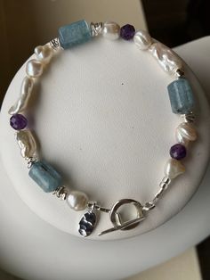 "This bracelet combines freshwater pearls in several shapes with smooth barrels of opalescent pale turquoise apatite and faceted purple amethyst. Stacks of irregular silver disks provide added visual appeal. A small sterling silver oval charm provide a little something extra.  This bracelet is 8 inches long, is strung on jeweler's wire and has a sterling silver toggle clasp. Item number 0520-BR5 [NOTE: We are always happy to resize any bracelet to ensure a great fit; Just leave us a \"Note to Se Beaded Ideas, Pale Turquoise, Freshwater Pearl Bracelet, Blue Jewelry, Brass Pendant, Blue Bracelet, Toggle Clasp, Amethyst Gemstone, Gemstone Bracelet