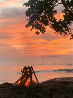 there is a fire pit on the beach at sunset