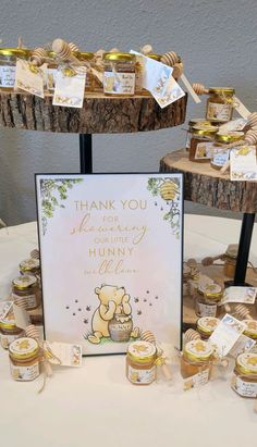 a table topped with lots of jars filled with honey next to a thank you sign