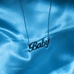 the word baby is displayed on a blue satin material with a chain attached to it