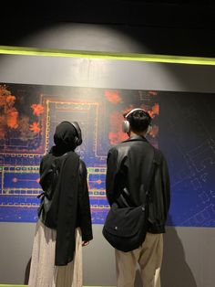 two people standing in front of a wall with a map on it and headphones to their ears