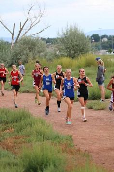 a group of people running down a dirt road