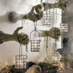 several hanging lanterns with plants and candles in them