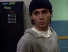 the young man is wearing a beanie and standing in front of a locker door