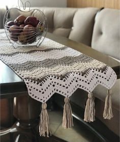 a crocheted table runner with tassels sits on a dining room table