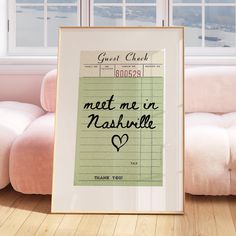 a framed poster with the words meet me in nashville on it next to a pink couch