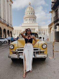 a woman standing in front of an old car with the capitol building in the background