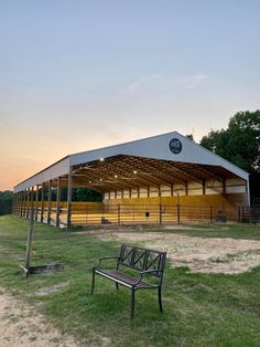 a wooden bench sitting in front of a metal structure on top of a grass covered field