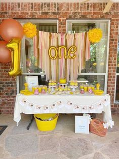 a table topped with balloons and cake next to a brick wall in front of a door