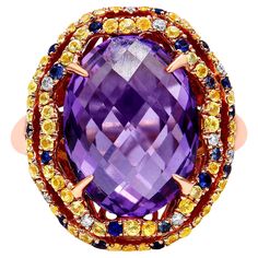 There are no words to truly describe this vividly colorful ring set in 18K Yellow and Rose Gold. The ring starts with a masterfully cut, checkboard purple amethyst set with 4 claw prongs. This magnificent purple stone measures 12mm x 11mm and gives off flashes of deep purple. The centerpiece is then finished with a yellow gold halo complete with a dazzling array of blue and yellow sapphires and white diamond accents. The entire piece sits on a rose gold band. You’ll never see another ring like t Colorful Ring, Amethyst Cocktail Ring, Sapphire And Diamond Band, Diamond Ring Cuts, Amethyst Set, Purple Amethyst Ring, Purple Rings, Purple Quartz, Diamond Fashion Rings