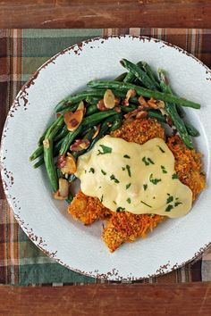 a white plate topped with meat covered in gravy next to green beans and potatoes