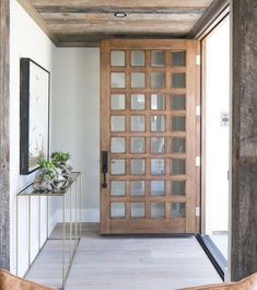 a wooden door with glass panels in a hallway next to a mirror and planter