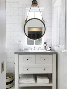 a white bathroom with a round mirror above the sink