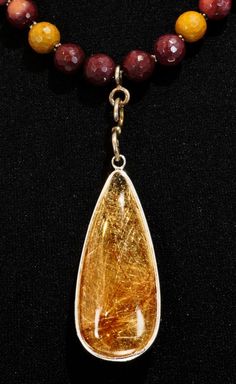 Rutilated Quartz is a clear Quartz stone filled with rutiles - straw-like golden streaks throughout the stone.  Very beautiful.  Each stone unique! This handsome teardrop pendant is Sterling Silver, filled to the brim front and back with domed  Rutilated Quartz in shades of gold to rust. The bail is aged Sterling and is handmade.  The necklace contains varying shades of Mookaite in faceted rounds, alternating with teeny Sterling spacers.  The clasp is aged Sterling hook and eye. The pendant and long bail measure 3" and the necklace is approx. 19" in length. Luxury Elegant Amber Crystal Necklaces, Shades Of Gold, Teardrop Pendant, Rutilated Quartz, Quartz Stone, Clear Quartz, Jewelry Necklaces, Necklaces, Pendant Necklace