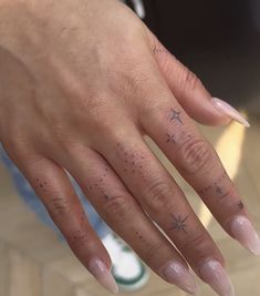 a woman's hand with a star tattoo on her left ring finger and pink manicures