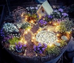 a small garden with flowers and lights in the center is displayed on top of a barrel