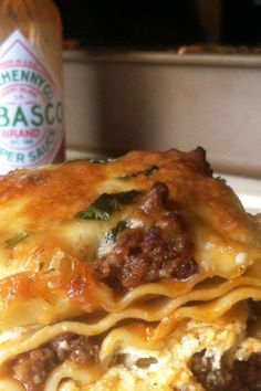 a close up of a plate of food with lasagna and sauce in the background