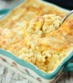 a spoon full of macaroni and cheese is being lifted from a casserole dish