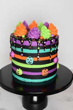 a multi - colored halloween cake on a black plate