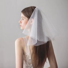 a woman wearing a veil and dress with her back to the camera, looking down