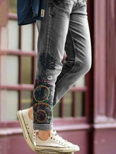 a woman's feet with colorful embroidered jeans and sneakers