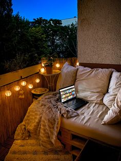 a laptop computer sitting on top of a bed covered in pillows and blankets next to candles