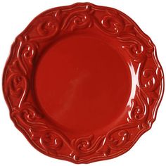 a red plate with an ornate design on the rim and bottom, sitting on a white surface