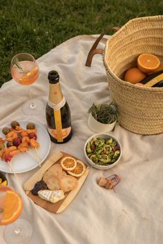 an outdoor picnic with oranges, wine and food