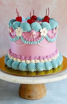 a pink and blue cake with cherries on top