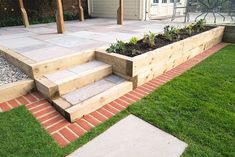 an outdoor garden area with steps and plants in the planter boxes on the grass