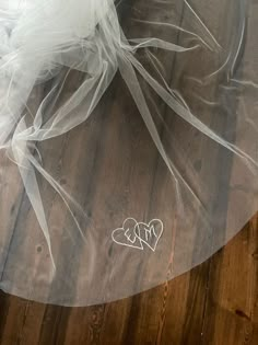 a white veil on top of a wooden floor with two hearts drawn on the fabric