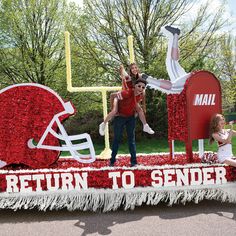 two women and a man are standing on top of a float with the words return to sender