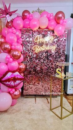 a birthday party with pink and gold balloons on the wall, an image of a woman's face