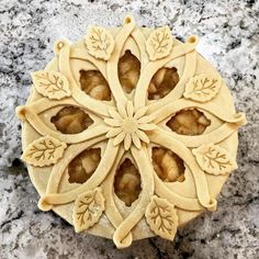 an intricately designed cookie with leaves on it sitting on a marble counter top, ready to be cut into smaller pieces