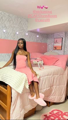 a woman sitting on top of a bed in a pink room with white and gray walls