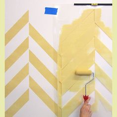 a person is painting a wall with yellow and white chevron stripes on the walls