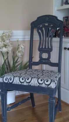 a blue chair sitting on top of a hard wood floor next to a potted plant