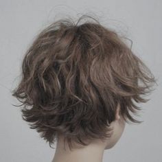 the back view of a wig with wavy hair on display in front of a white wall