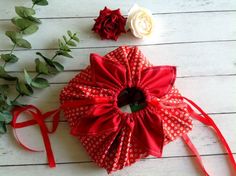 a red ribbon tied around a flower on top of a white wooden table next to two roses