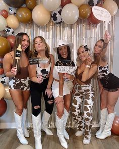 four women dressed in cowgirl costumes posing for a photo with balloons and streamers behind them