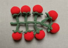 crocheted strawberries are arranged in the shape of a snowflake with green stems and red berries